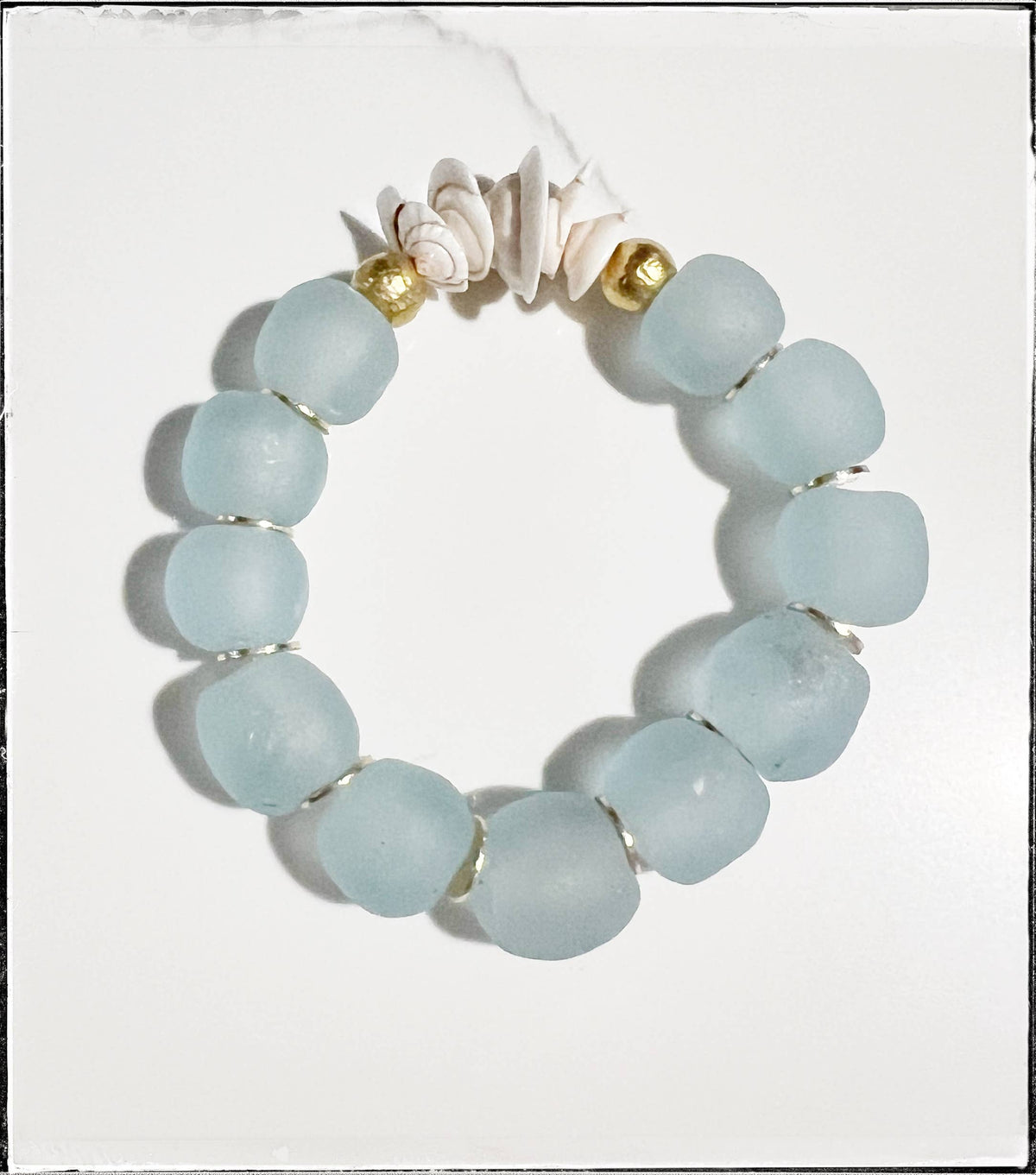 A handmade beaded bracelet featuring turquoise stones rests on a white surface.