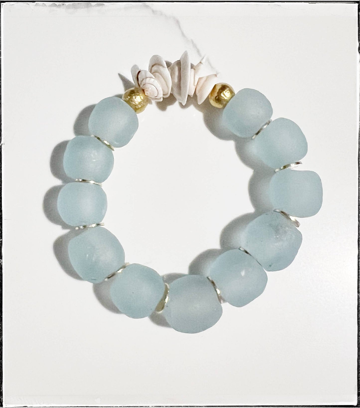 A handmade beaded bracelet featuring turquoise stones rests on a white surface.
