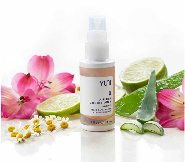 Spray bottle. 2fl oz of Yuni Air Dry Conitoner hair mist surrounded by fruit and flowers